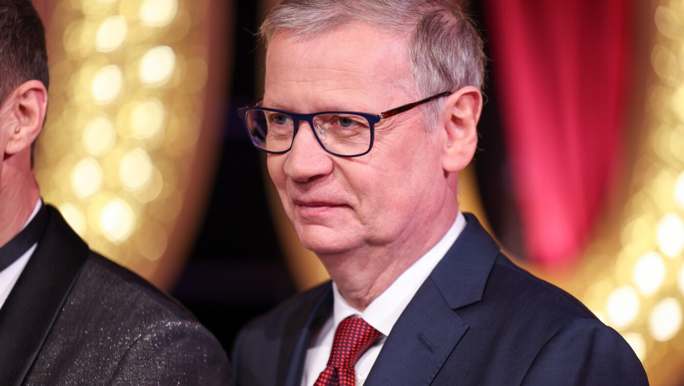 Günther Jauch mit Brille, Anzug und Krawatte befindet sich neben einem anderen Mann