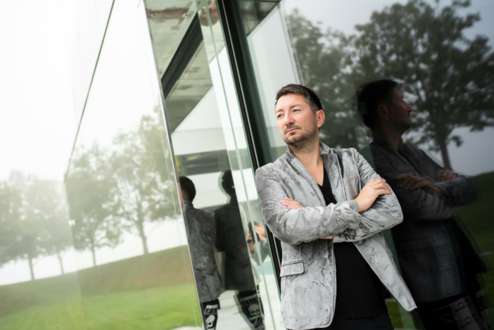 Walter Temmer Wahrheit Walter Temmer lehnt mit grauem Sakko an einer Glasfront