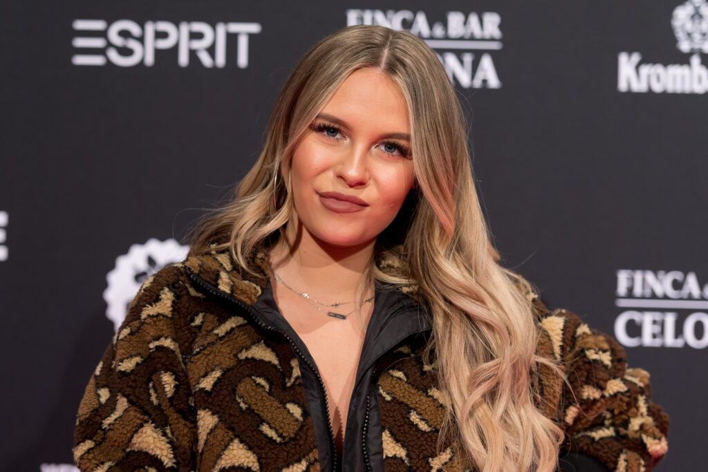Dagi Bee posiert vor einer Werbewand