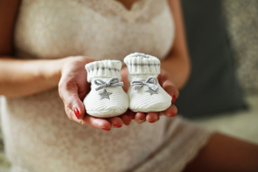 Frau hält kleine Baby-Schuhe in den Händen