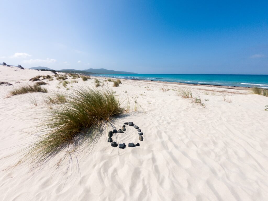weißer Standstrand mit Herz aus Steinen