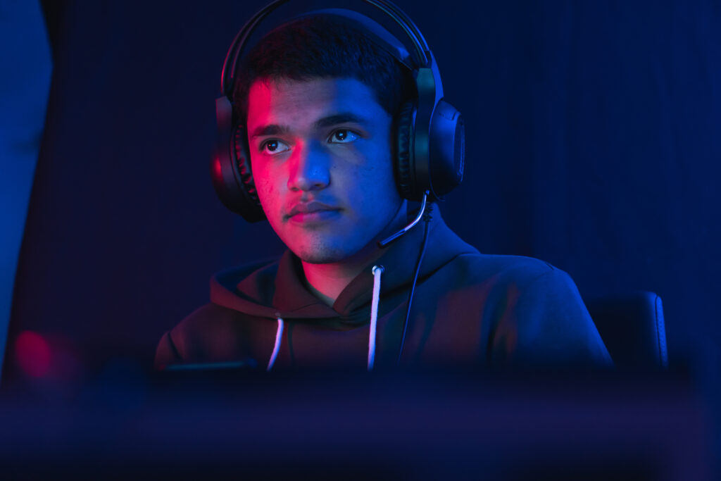 Junger Mann mit Kopfhörern beim Streamen in Dunkelheit