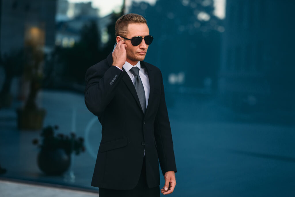 Dunkel gekleideter Bodyguard hält Hand zu Ohr