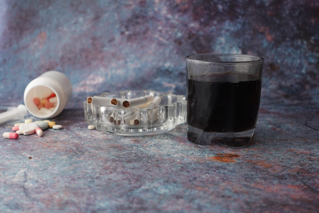 verschüttete Tablette, Aschenbecher mit Zigaretten und ein Glas mit Kaffee