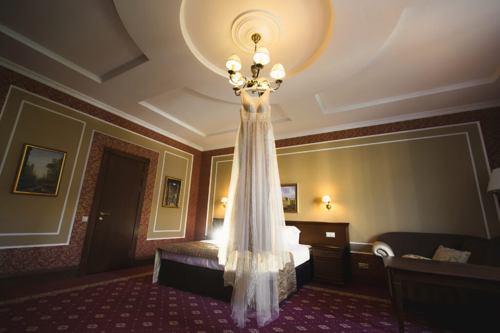 Luxuriöses weißes Hochzeitskleid hängt in einem Hotelzimmer