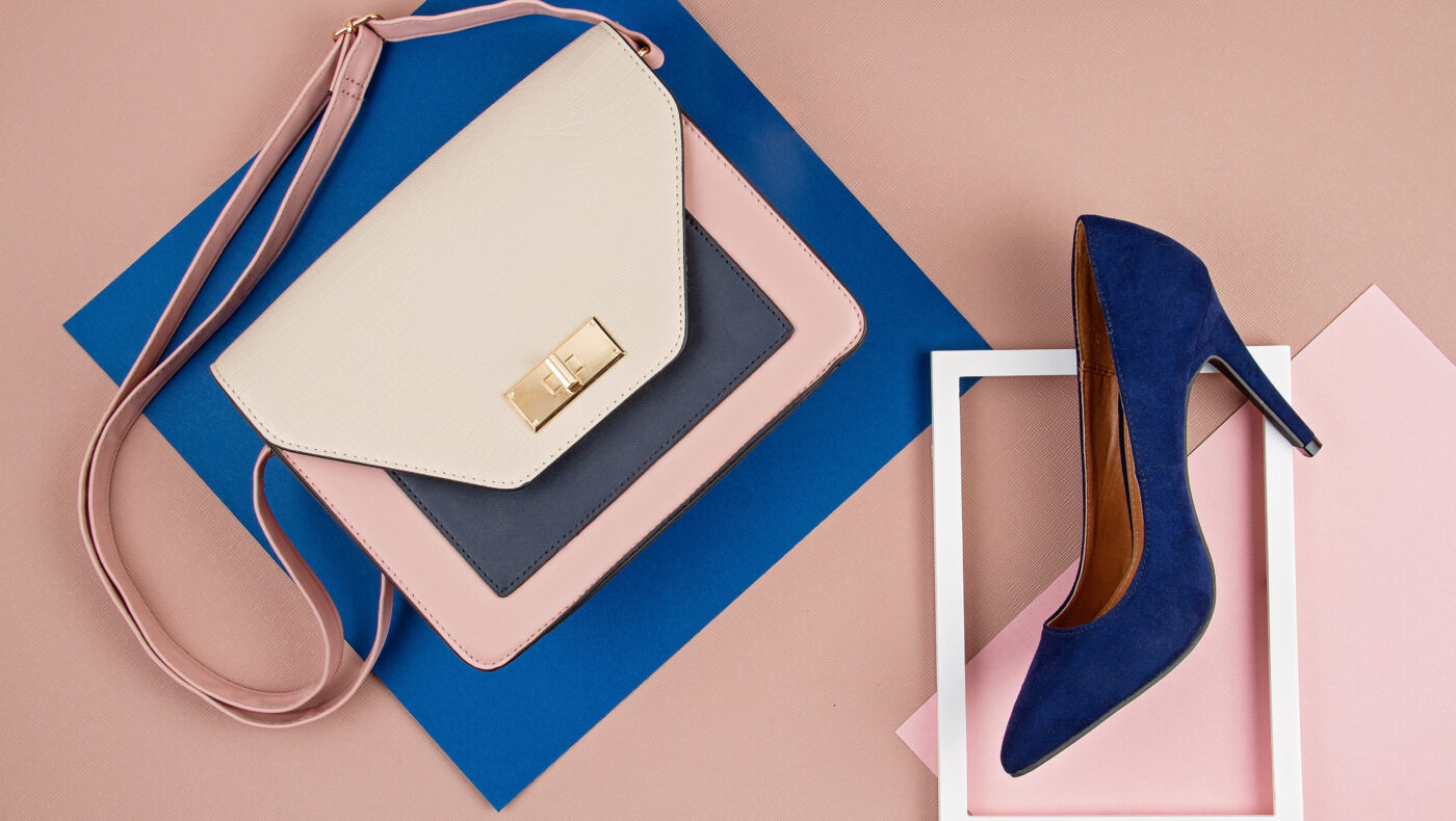 Baluer Highheel in einem Fotorahmen. Daneben eine blaue Handtasche