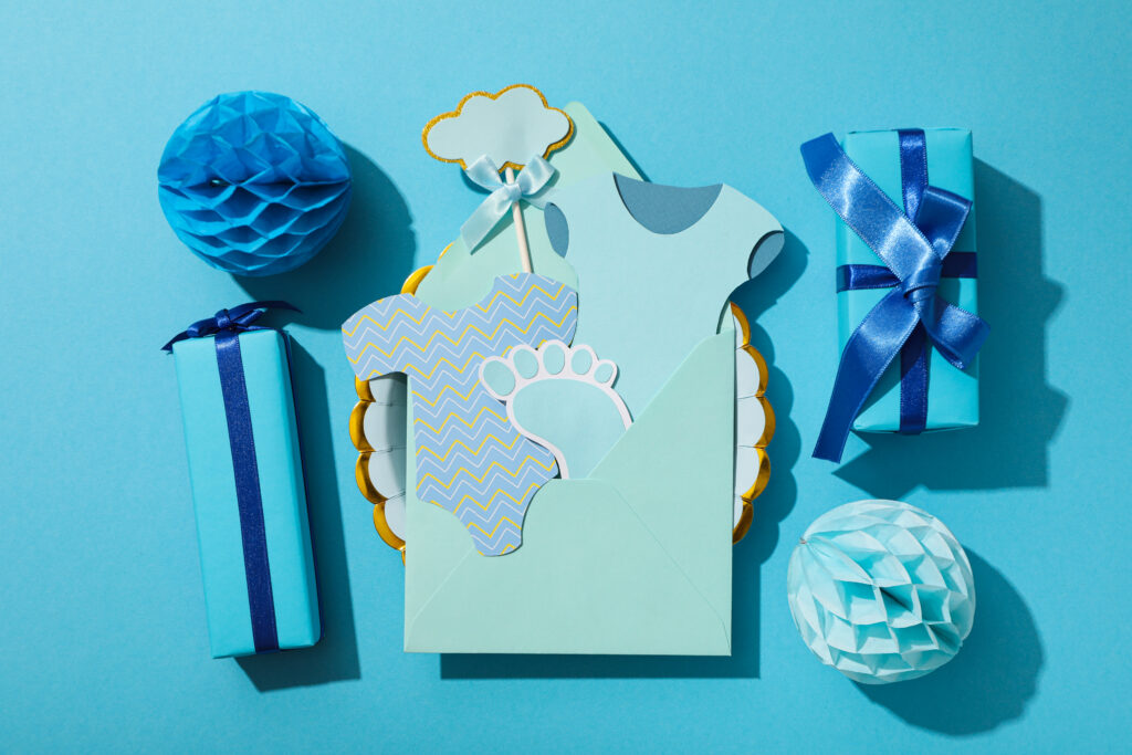 Blauer Hintergrund auf dem zwei blaue Deko-Bällchen, zwei blau eingepackte kleine Geschenke und eine Glückwunschkarte liegen