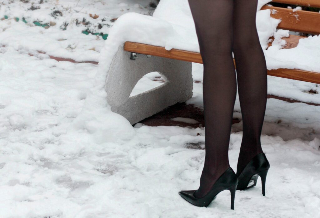 Frau mit schwarzen Strümpfen und schwarzen Highheels.