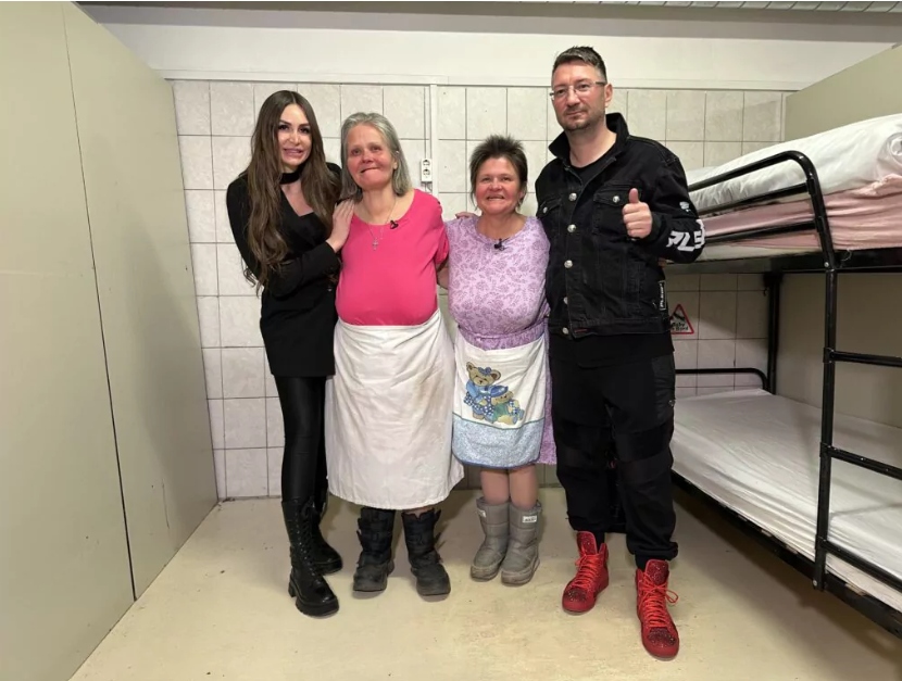 Walter steht mit Susi Temmer und zwei Damen in einer Notschlafstelle und hält den Daumen in die Höhe