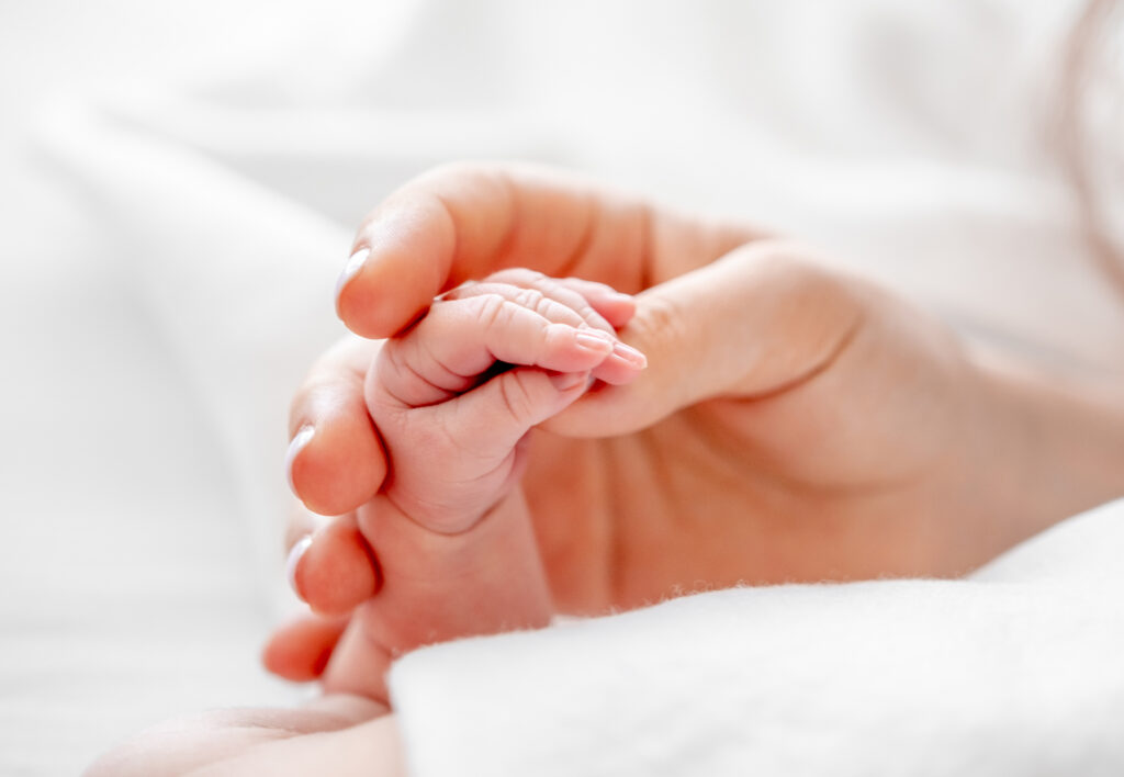 Erwachsenenhand hält Babyhand