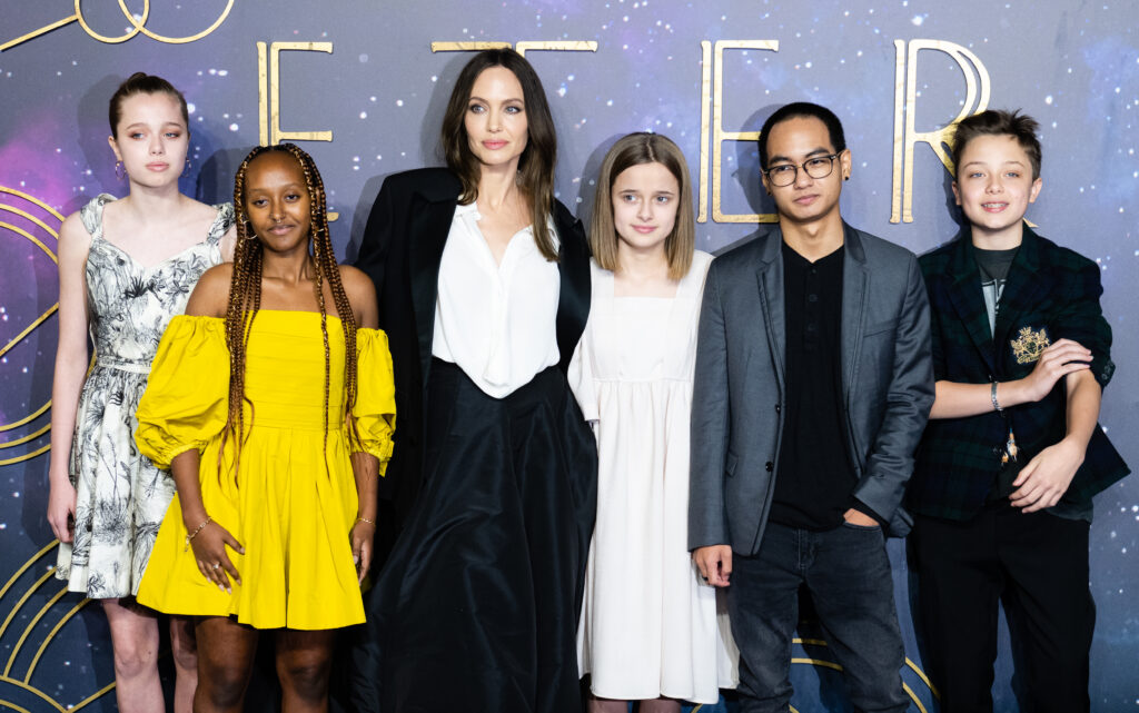 Angelina Jolie mit ihren fünf Kindern vor einem Plakat von Eternal 