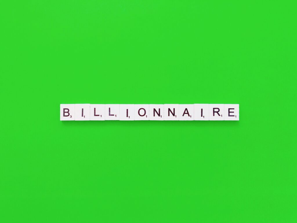 grüner Hintergrund; darauf die Buchstaben Billionnaire; jeder Buchstabe auf einem Würfel, unter dem Buchstaben sind Zahlen