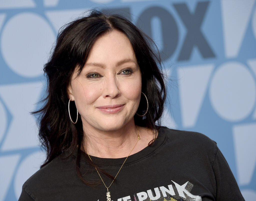 Shannen Doherty mit schwarzem Oberteil lächelt in die Kamera