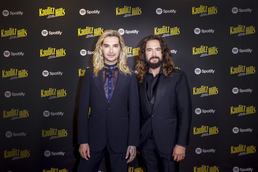 Tom und Bill Kaulitz posieren vor Werbewand