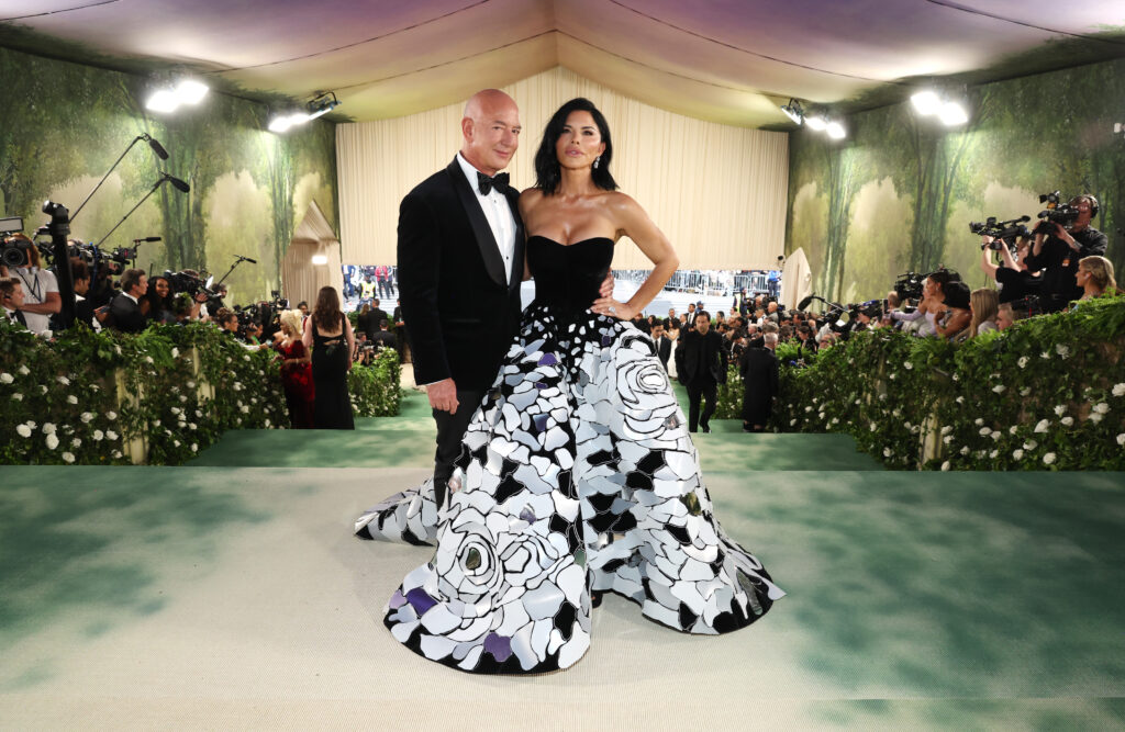 Jeff Bezos mit einer Dame die ein auffallendes Kleid in schwarz-weiß trägt