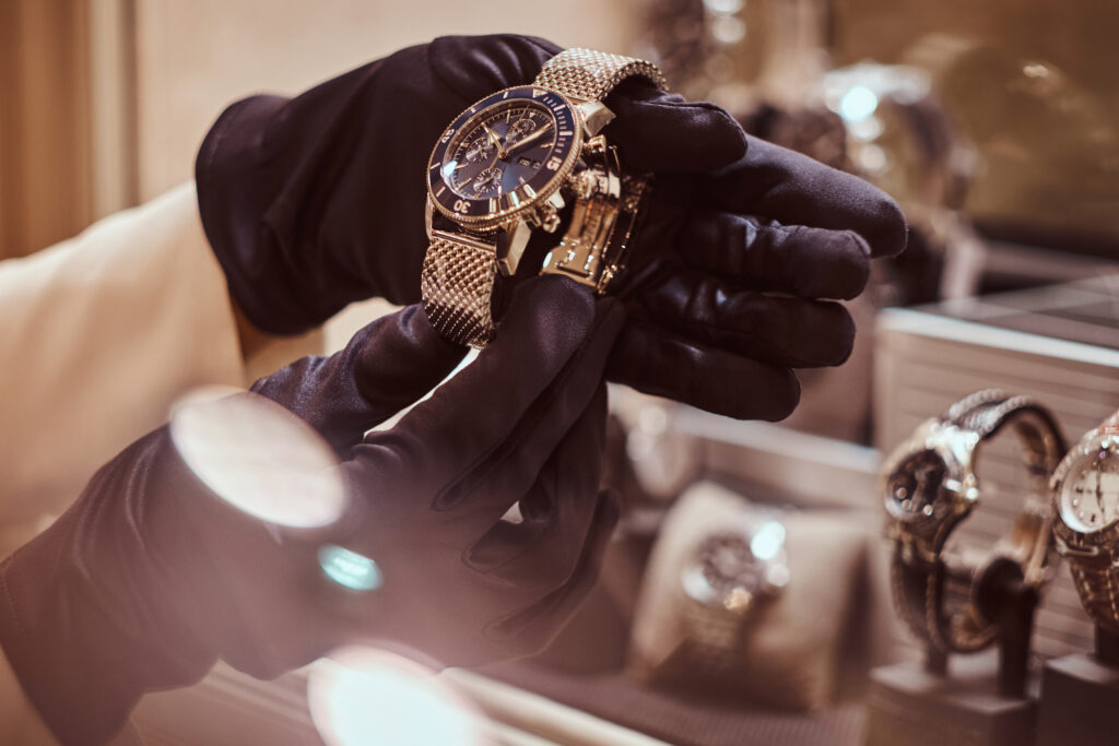 schwarze Baumwollhandschuhe in zwei Händen die eine sehr exklusive Uhr halten