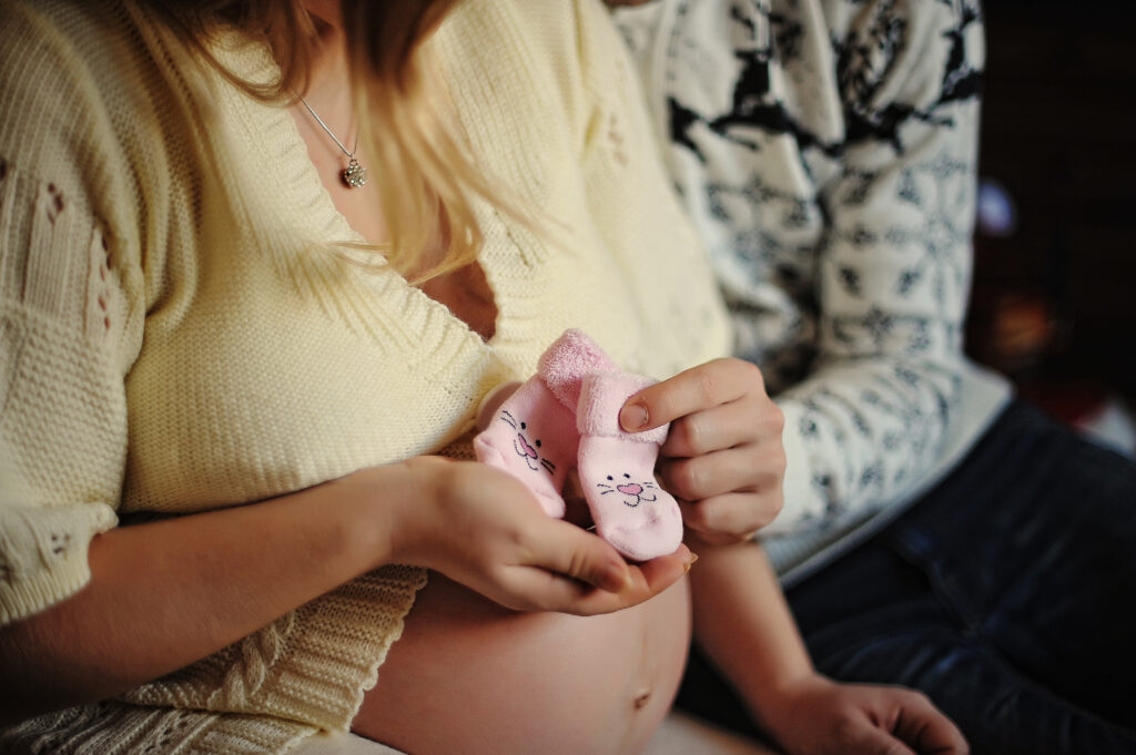 Babybauch und kleine Socken in rosa