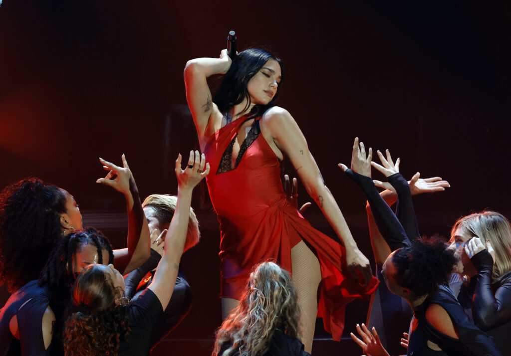 Dua Lipa in rotem Kleid auf einer Bühne vor ihren Fans