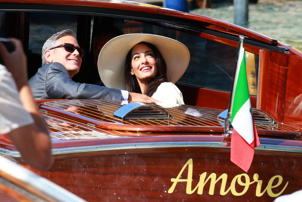 George Clooney und Amal in einem kleinen Boot mit der Aufschrift Amore