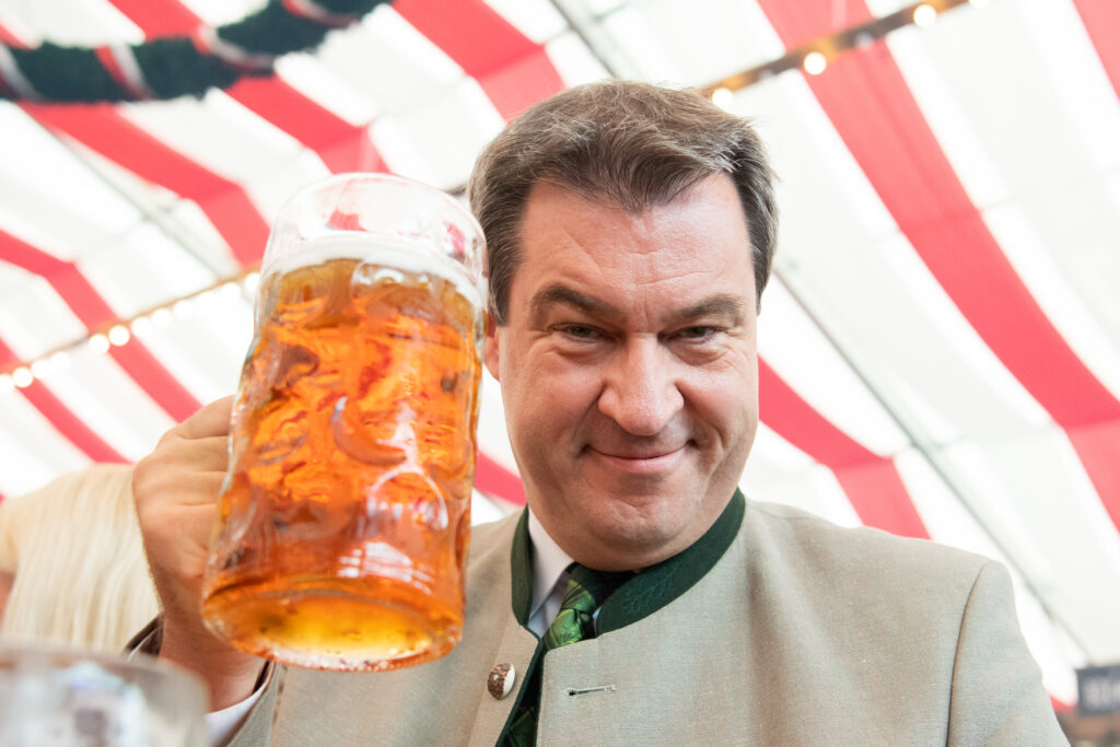 Markus Söder mit einem großen Bierglas in der Hand lacht in die Kamera