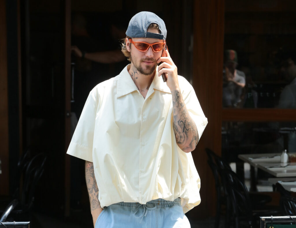 Justin Bieber mit weißem Hemd und Handy in der Hand