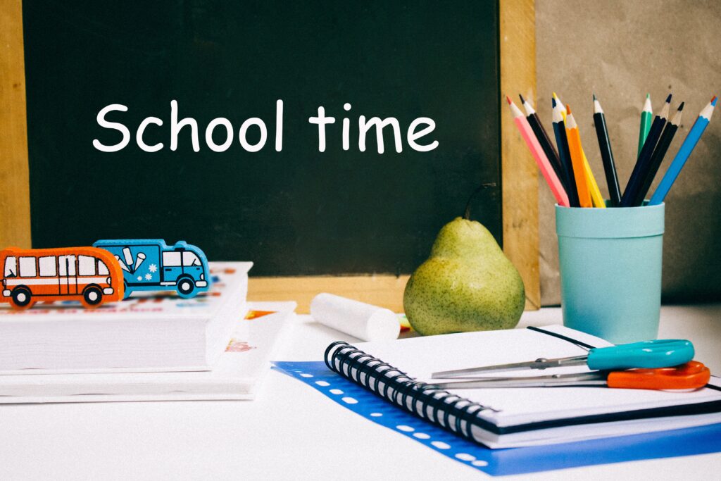 school time mit Stiften, einer Birne, zwei Radiergummi in Lkw Form und zwei Scheren auf Büchern