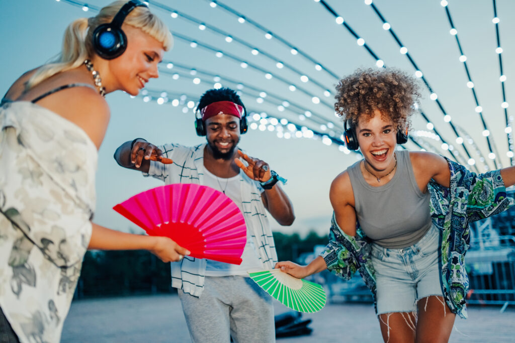 3 Fans die zu Musik jubeln und Tanzen und Fächer in der Hand haben